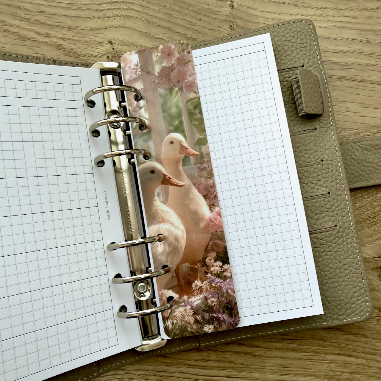 Open planner with grid pages and a decorative insert featuring ducks on a wooden surface